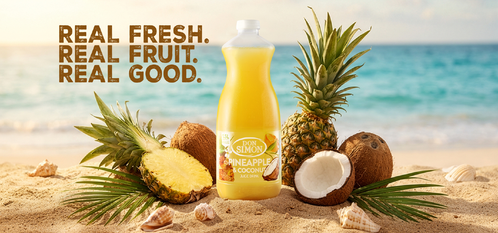 A bottle of Don Simon Pineapple & Coconut juice sits on sand, surrounded by pineapples, coconuts, and palm leaves, with an ocean and blue sky in the background. Text reads: REAL FRESH. REAL FRUIT. REAL GOOD.