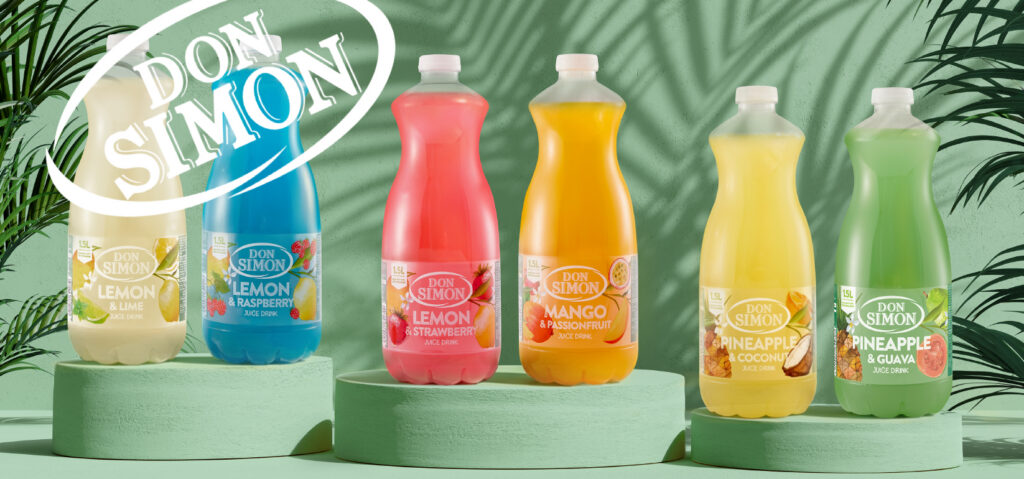 Five colorful bottles of Don Simon juice drinks (Lemon & Lime, Lemon & Raspberry, Lemon & Strawberry, Mango & Passionfruit, Pineapple & Coconut, Pineapple & Guava) displayed on green platforms with leafy shadows.